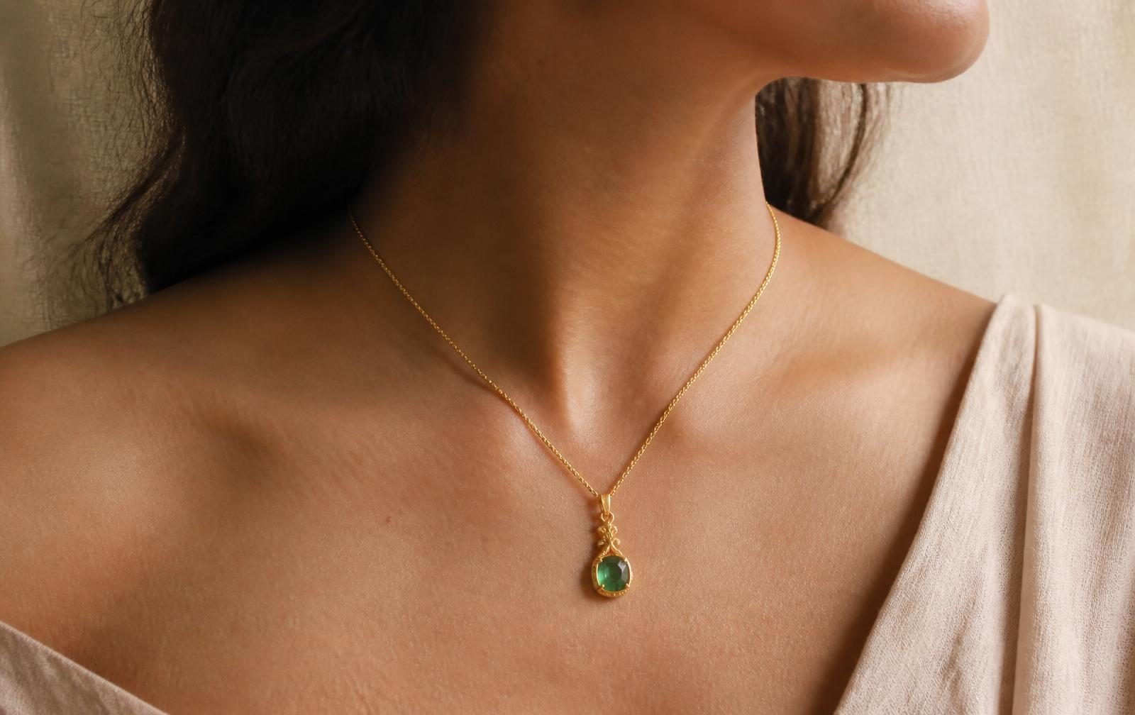 A 22K gold ring set with a natural emerald resting on deep green silk